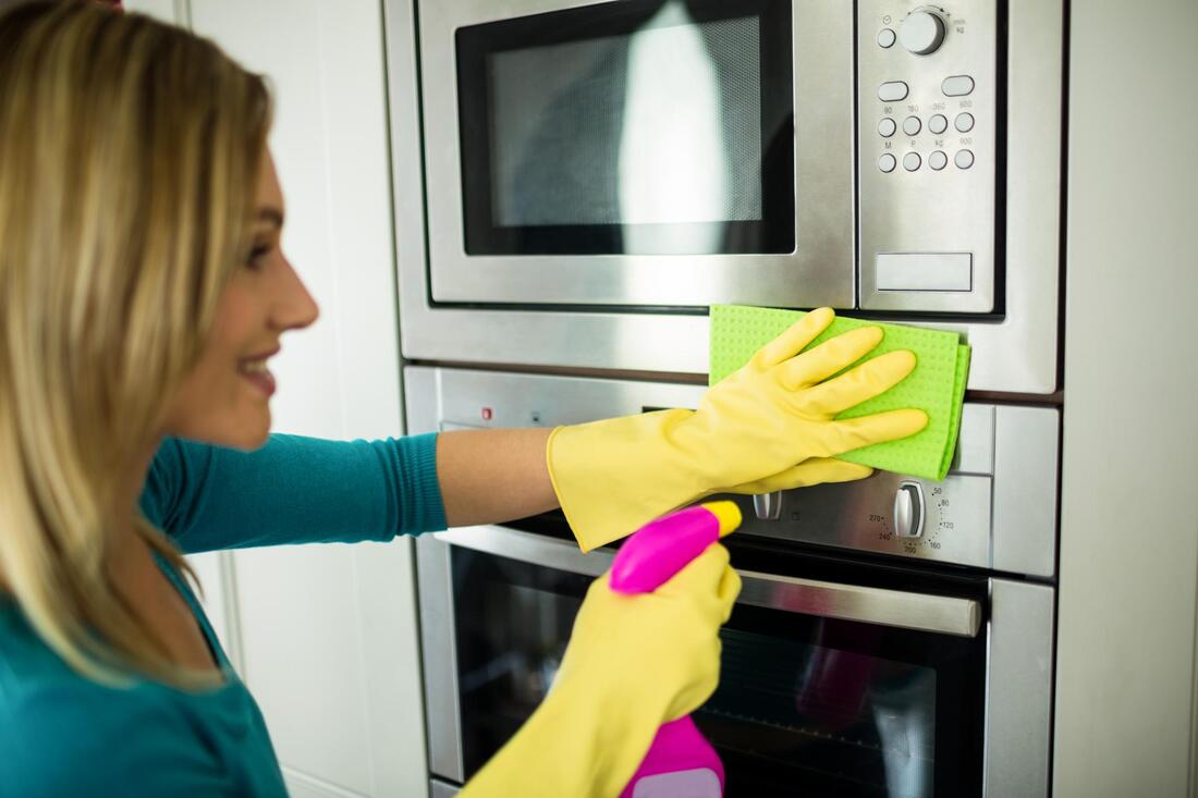 a woman cleaning an oven with a sponge